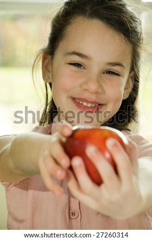 brown haired child presenting an apple.Healthy lifestyle image.