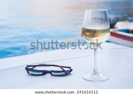 glass of wine on the sea and sunglasses