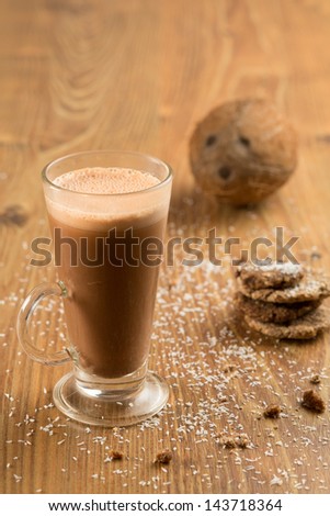 Healthy coconut drink in a glass placed on a wooden table sprinkled with coconut bit