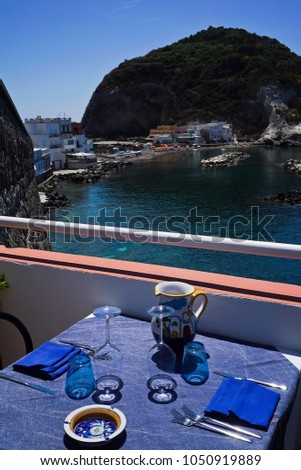 Beautiful view of the blue lagoon from the Mediterranean restaurant. In the foreground there is a table with a blue tablecloth and beautiful blue and white dishes. Vertical photo.