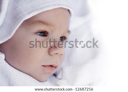 Side portrait of a beautiful baby covered with white towel