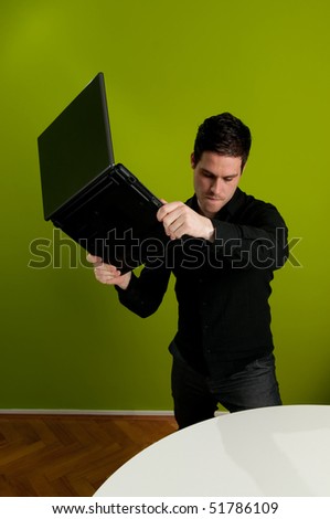 Frustrated man trashing his laptop on table