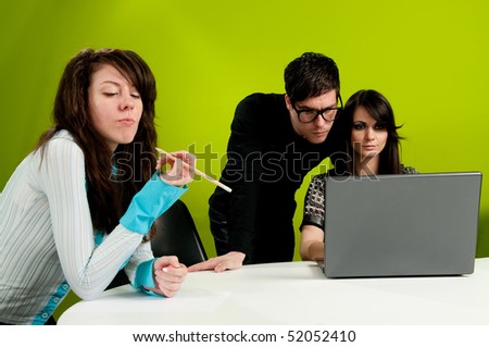 Group of young people busy in the office working on computer and girl writing with pen