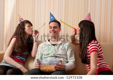 Two girls and a guy in party hats having a birthday party