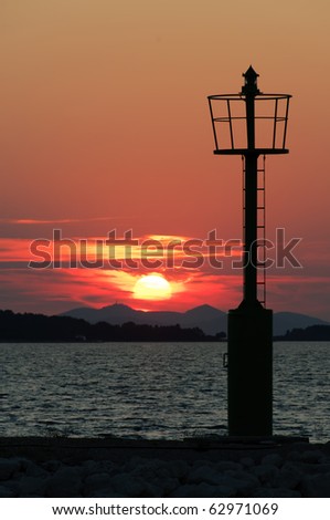 Light beacon with sea and red sunset in background