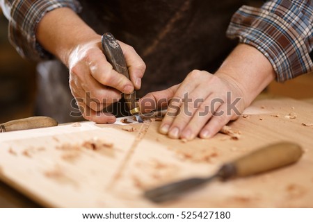Carpenter with chisel in the hands on the workbench