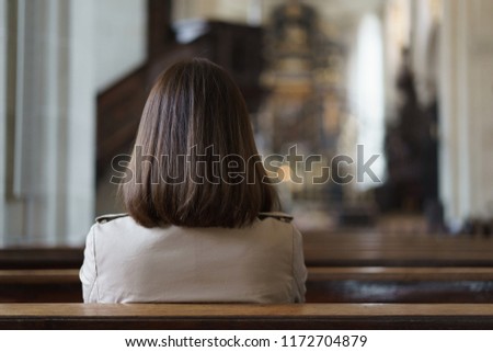 A Christian girl is sitting and praying with humble heart in the church.