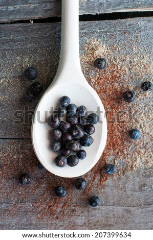 Wooden spoon with seeds of juniper on wooden spoon