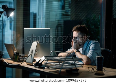 Fatigue man in shirt rubbing face while watching computer totally exhausted working late at night.