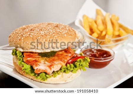 Burger with salmon, lettuce, tomatoes and deep-fried potato