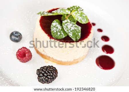 Cheesecake with bilberry, raspberry, blackberry, powdered sugar and mint twig