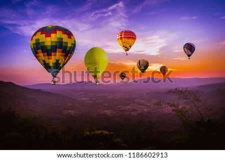 Colorful hot air Balloons  flying above green mountain at sunset time with  beautiful twilight sky background