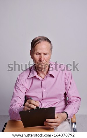 Businessman sitting at table and writing  against grey background
