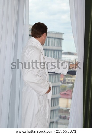Back Portrait of a man in a white bathrobe in front of a window
