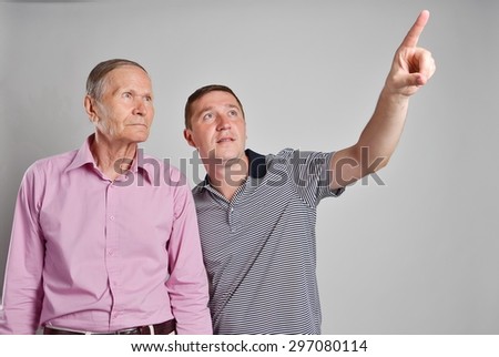Young man pointing upwards. Old man looking up