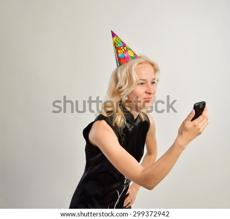 Portrait of a  young woman with a cell phone and birthday hat