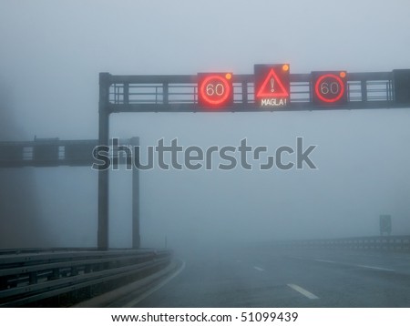 Notification traffic sign on a highway at strong fog