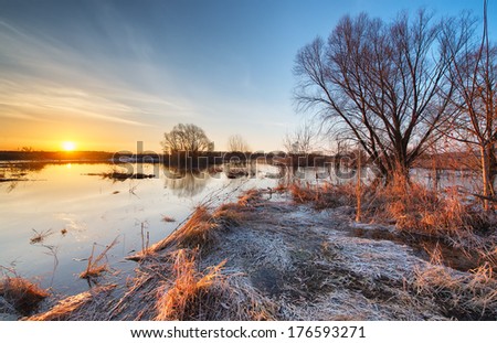 Early spring landscape. Sunrise on a flooded river with thawed ice.