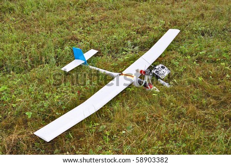 Red and white radio controlled airplane with methanol engine on a grassy field.