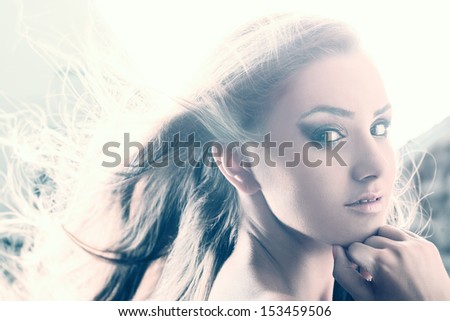 Young woman beauty portrait against strong light with hair blown out