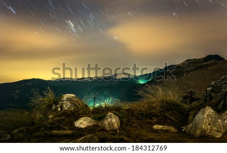 Beautiful night scenery with mountains under the cloudy sky with star trails