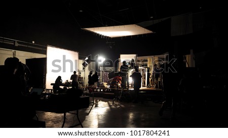 Behind the scenes of video shooting production crew team silhouette and camera equipment in studio.