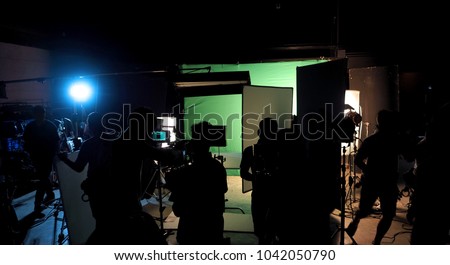 Behind the scenes or the making of film video production and movie crew team working in silhouette of camera and equipment set in studio.