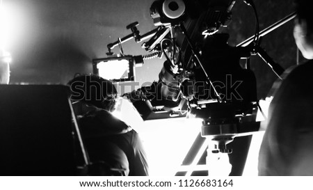 Blurry images of silhouette people film crew team working behind the scenes for shooting video production with professional equipment camera and lighting in the studio.