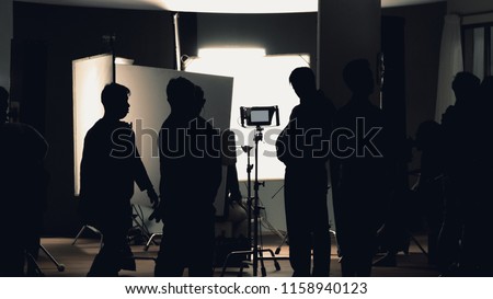 Video production behind the scenes which film crew team in silhouette shooting or recording tv movie commercial with professional equipment such as high definition 4k camera with monitor in studio set