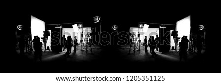 Silhouette images of video production behind the scenes or b-roll or making of TV commercial movie that film crew team lightman and cameraman working together with director in big studio