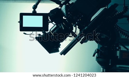 Silhouette images of video camera in tv commercial studio production which operating or shooting by cameraman and film crew team in set and prop on professional crane and tripod for pan tilt or shift