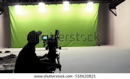 Camera man and tools and white floor and big green screen studio.