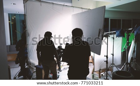 Behind the scenes of shooting video or movie production crew team and silhouette of camera and equipment in studio.