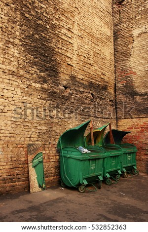 Green garbage bins at the brick wall in a courtyard in Saint-Petersburg, Russia.