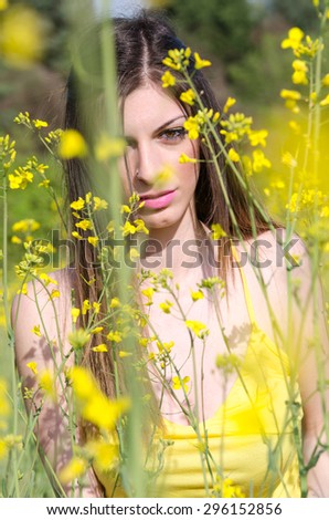Yellow blooming field, cute fit young lady in yellow shirt, looking through the yellow flowers
