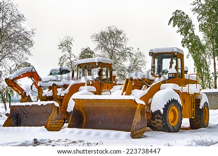 Two bulldozers and one excavator in the snow field