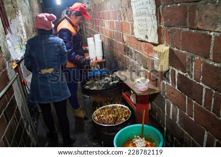 Changsha, Hunan province, China - January 10, 2014: a mother and daughter are processing stinky tofu, a kind of delicious snack in Changsha, in a small poor corridor.