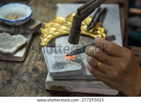 SOMSAMAI GOLD IN SUKHOTHAI, THAILAND - May 2, 2015:  Goldsmith is welding a piece of gold with tweezers at Ban Thong Somsamai in Sukhothai.