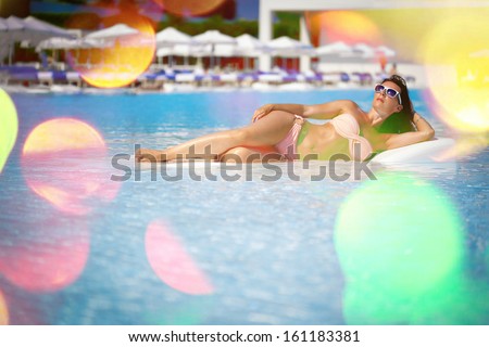 Beautiful young woman having a rest on the pool. Additional post-processing effect.