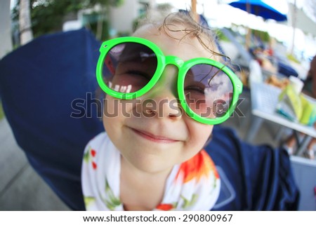 Portrait of a funny smiling baby with glasses. Fish-eye lens. Focus on lips.