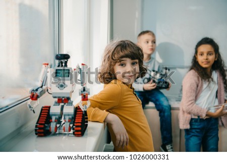 adorable little schoolboy with diy robot on stem education class