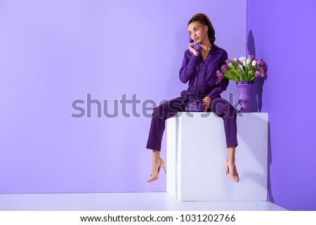 fashionable beautiful  girl talking on rotary phone and sitting on cube with tulips