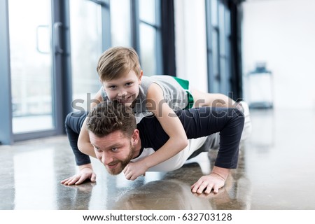 Man doing push ups with boy on his back