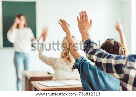 group of students raising hands in class on lecture