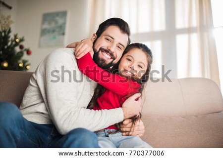 happy father and daughter hugging and sitting on sofa