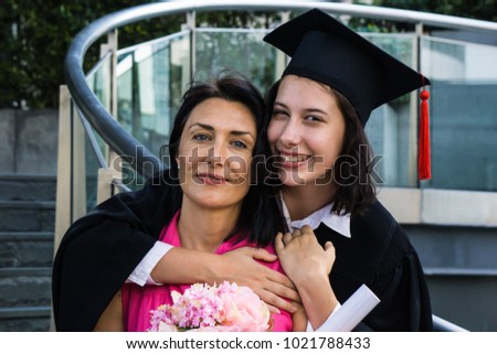 Young beautiful woman graduate hugging her mother at graduation ceremony, University Graduation Certificate Hugging Success Family Concept