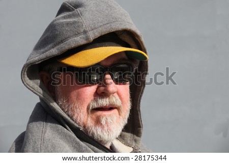 Man with white beard wearing sunglasses, baseball cap, and hoodie with copy space