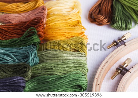 Embroidery threads with wooden hoops and cross stitch fabric for concepts of leisure time and needlecrafts