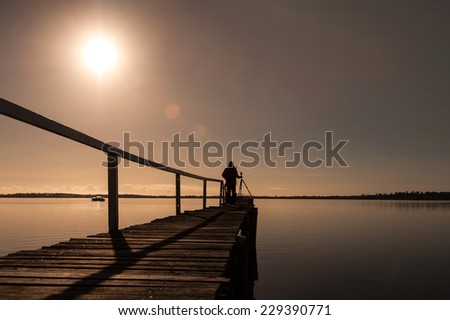 stand alone silhouette photographer on wooden jetty