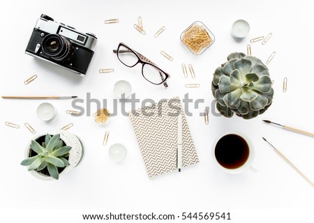 desk workspace with succulent, retro camera, coffee, diary, glasses and golden clips on white background. flat lay, top view